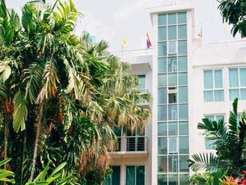 a tall white building with palm trees in front of it at P.K. Garden Home in Bangkok