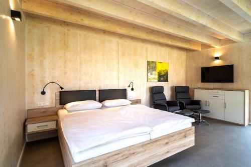 a bedroom with a large bed and two chairs at Feriendorf am Sonnensee in Leipheim