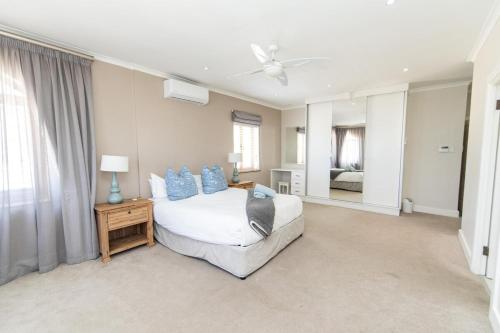 een slaapkamer met een bed met blauwe kussens bij Villas Marina On The Beach in Port Elizabeth