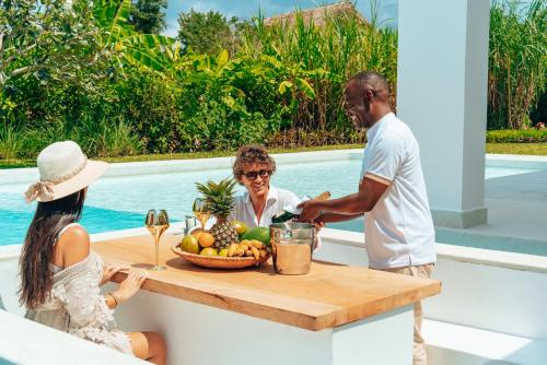 a man and woman standing around a table with a bowl of fruit at Ycona Eco-Luxury Resort, Zanzibar in Dikoni