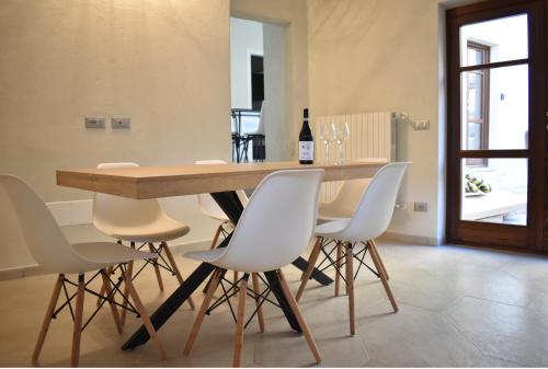 a dining room table with white chairs and a bottle of wine at Ca' Ronzini in Castiglione Falletto