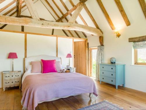 ein Schlafzimmer mit einem großen Bett mit rosa Kissen in der Unterkunft The Oast House - Hartley Wine Estate in Alton