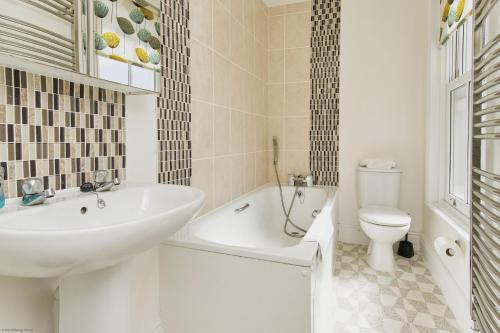 a bathroom with a sink and a tub and a toilet at Woodleigh in Sandown