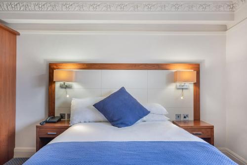 a bed with a blue pillow on top of it at The Riverside in Kendal