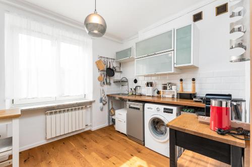 a kitchen with white cabinets and a washer and dryer at Elektoralna 19A by Homeprime in Warsaw