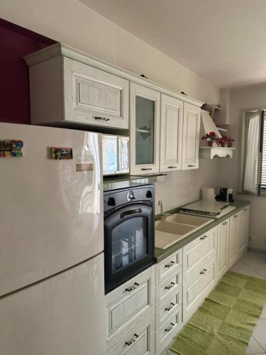 eine Küche mit weißen Schränken und einem TV mit Kühlschrank in der Unterkunft Casa vacanza Ylenia in Mascali