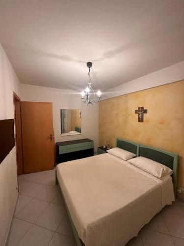 ein Schlafzimmer mit einem großen Bett und einem Kreuz an der Wand in der Unterkunft Casa vacanza Ylenia in Mascali