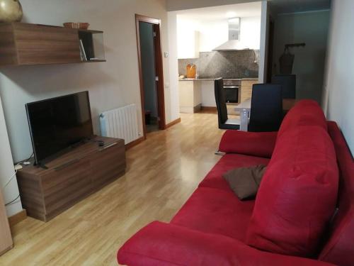 a living room with a red couch and a television at Pis a Bellpuig in Bellpuig