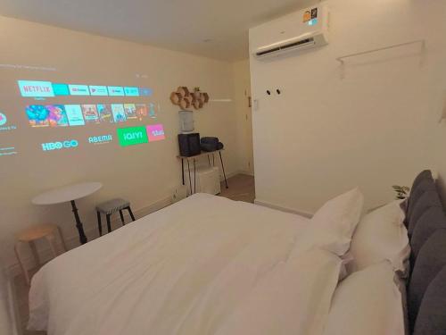 a bedroom with a white bed and a table and stool at The White Den Sukhumvit 44 in Bangkok