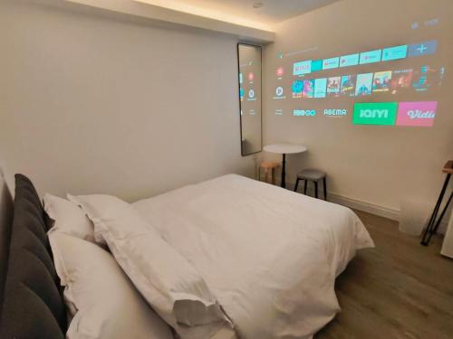 a bedroom with a white bed and a large screen at The White Den Sukhumvit 44 in Bangkok