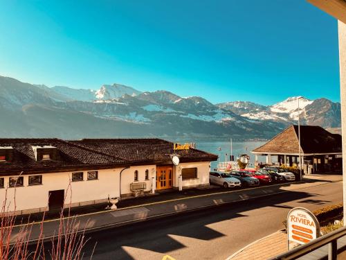 a street with buildings and cars parked in front of mountains at Seehotel Riviera at Lake Lucerne in Gersau