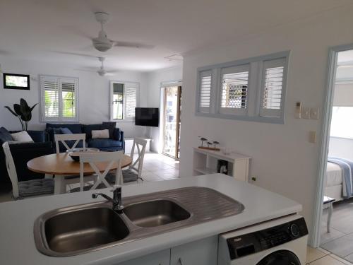 uma cozinha com um lavatório e uma sala de estar em Airlie Apartments em Airlie Beach