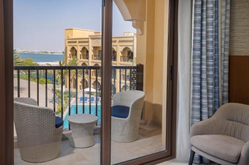 a balcony with chairs and a view of a pool at DoubleTree by Hilton Resort & Spa Marjan Island in Ras al Khaimah