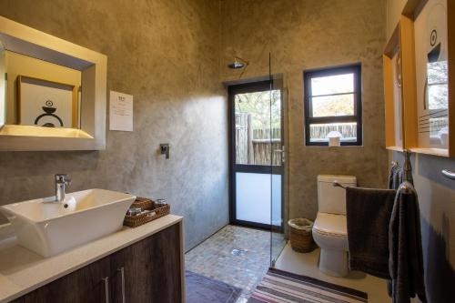 a bathroom with a sink and a toilet and a window at Moya Safari Villa in Hoedspruit