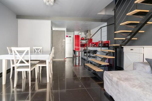 eine Küche und ein Esszimmer mit einem Esstisch und einer Treppe in der Unterkunft appartement de la barque bleue in Le Grau-du-Roi