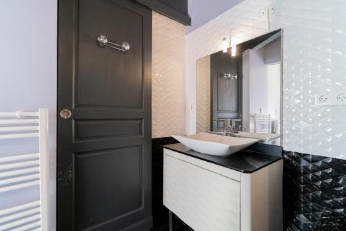W łazience znajduje się umywalka i lustro. w obiekcie appartement de la barque bleue w mieście Le Grau-du-Roi