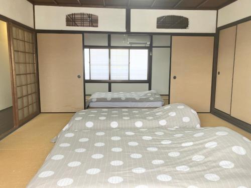 two beds in a room with two windows at Private reservation near KIX "Wakeikan" in Izumi-Sano