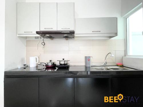 a kitchen with white cabinets and a black counter top at KLIA Ehsan Residences Sepang Nilai in Sepang