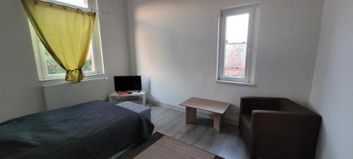 ein Schlafzimmer mit einem Bett und einem Stuhl sowie zwei Fenstern in der Unterkunft Ap 4 35qm bei Oschersleben und Helmstedt in Ausleben