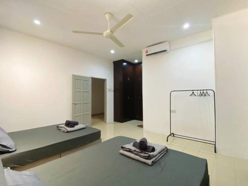 a room with two beds and a ceiling fan at Homestay 2 @Taman Teluk Intan in Teluk Intan