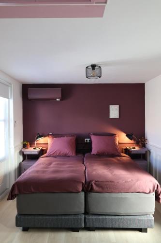 um quarto com uma cama com paredes roxas e duas mesas em B&B nr.15 em Vries