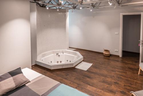 Avangarda Suites في بلغراد: غرفة كبيرة مع حوض استحمام على أرضية خشبية