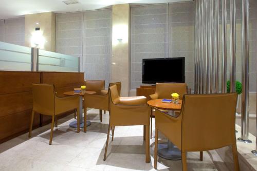 una sala de espera con mesas, sillas y TV en NH San Pedro, en Marbella