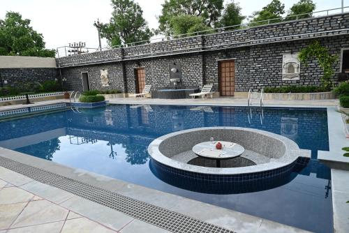 uma piscina com uma fonte em frente a um edifício em THE TRISHALA VILAS (A LUXURY BOUTIQUE HOTEL & SPA) em Ranakpur