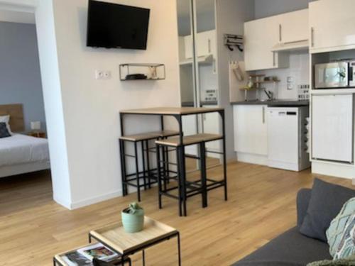 un salon avec un canapé et une table et une cuisine dans l'établissement Bel appartement proche gare et centre-ville, à Rambouillet