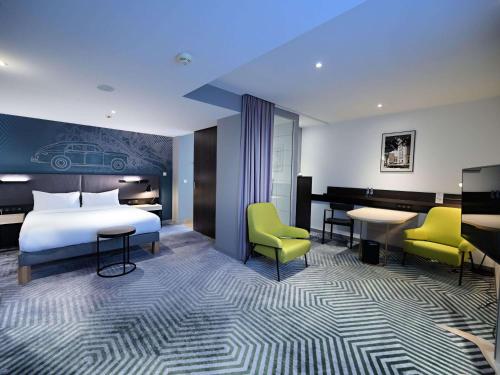 a hotel room with a bed and a desk and chairs at Mercure Warszawa Grand in Warsaw