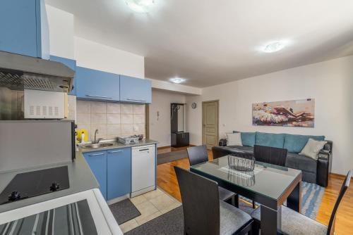 eine Küche und ein Wohnzimmer mit blauen Schränken und einem Tisch in der Unterkunft Apartment Maksi-Centar in Zlatibor