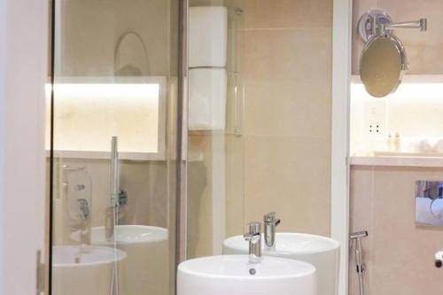 a bathroom with two sinks and a glass shower at Andalus Al Seef Resort & Spa in Abu Dhabi