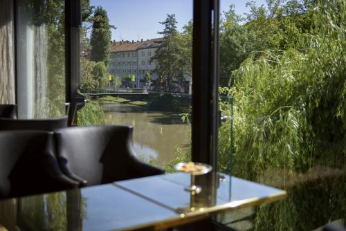 a table with a view of a river from a window at Insel-Hotel Heilbronn in Heilbronn