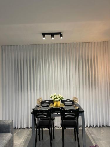 a table with chairs and a vase of flowers on it at דירת אירוח מפנקת בעיר אשקלון - 5 דקות נסיעה מהים in Ashqelon