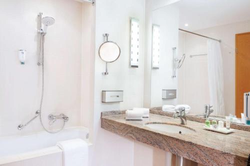 a white bathroom with a sink and a shower at NH Dresden Neustadt in Dresden