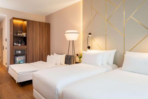 two beds in a hotel room with white pillows at NH Collection München Bavaria in Munich