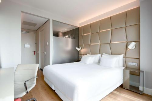 a bedroom with a large white bed and a chair at NH Collection Eindhoven Centre in Eindhoven