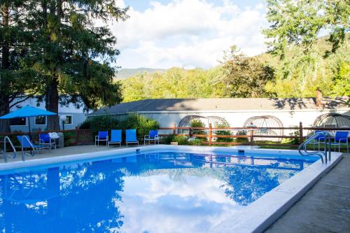 a swimming pool with blue chairs and a building at Woodwards White Mountain Resort, BW Signature Collection in Lincoln