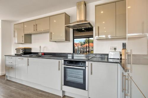 a kitchen with white cabinets and stainless steel appliances at Modern Penthouse in Wembley in London