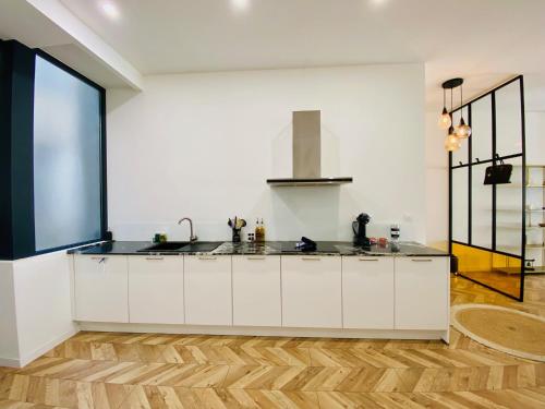 une cuisine avec des armoires blanches et un plancher en bois dans l'établissement ''Rousseau'' Superbe T2 climatisé au Théâtre Molière, à Sète