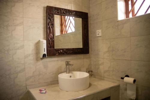 a bathroom with a sink and a mirror at Heritage Hotels Arua in Arua