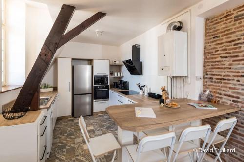 a kitchen with a wooden table and white cabinets at Suite Mana - Maui - Place Ducale in Charleville-Mézières