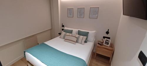 a small bedroom with a white bed and pillows at Kofradía By Kabia Gestión in Bermeo