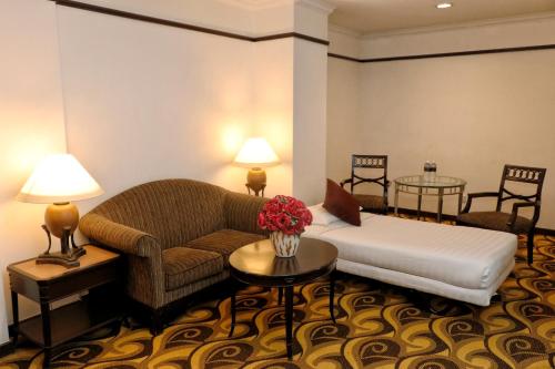 a hotel room with a bed and a couch and tables at Mardhiyyah Hotel and Suites in Shah Alam