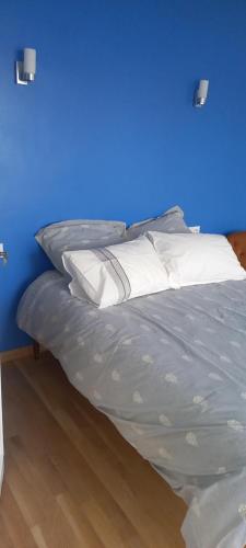 - un lit avec des oreillers blancs et un mur bleu dans l'établissement Chez Emile, à Brézins