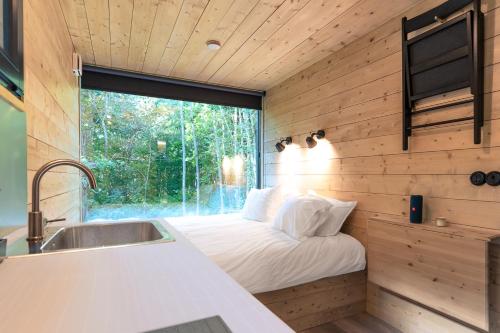 1 dormitorio en una casa pequeña con ventana en Chic Sauna Cabin Near the Sea - VULIN Cabin Nº01, 