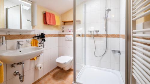 a bathroom with a shower and a toilet and a sink at Gästehaus Maier zum Bitscher in Rottach-Egern