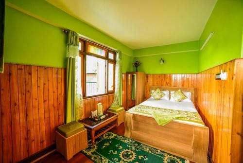 a bedroom with a bed and a green wall at GRG Tharbaling Homestay Darjeeling in Ghum