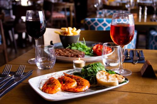 una mesa con dos platos de comida y dos copas de vino en The Kings Head Inn, home of The Acle Steak en Acle