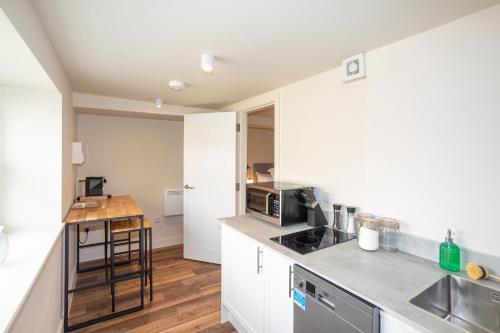 a kitchen with white cabinets and a counter top at 30 Chipping Norton - Luxury Holiday Apartments in Chipping Norton